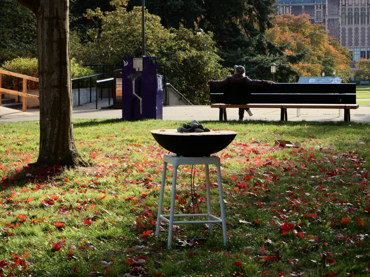SoundMat on a stool on a campus lawn, a person sitting on a bench in the distance