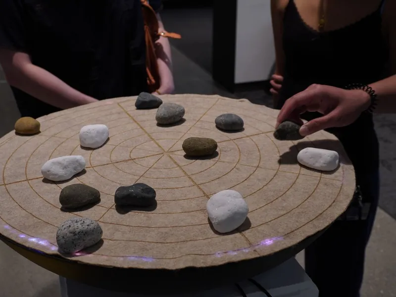 Hands placing stones on SoundMat, its LED ring glowing at the edge