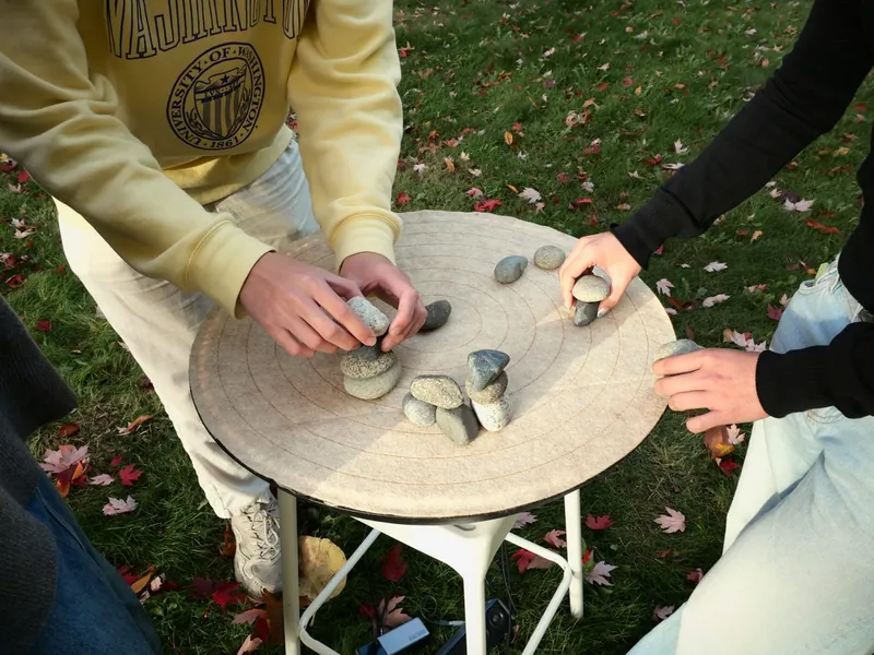 Two people stacking stones on SoundMat outdoors
