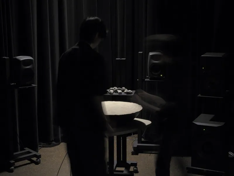 A person beside SoundMat in the dark lab, a tray of stones behind