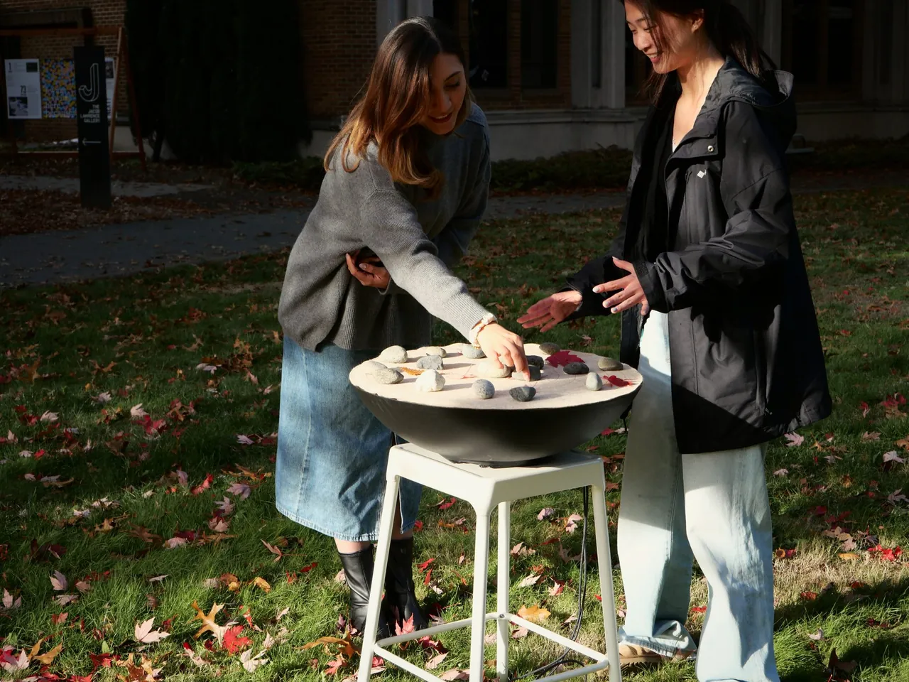 Two people laughing as they move stones on SoundMat outdoors